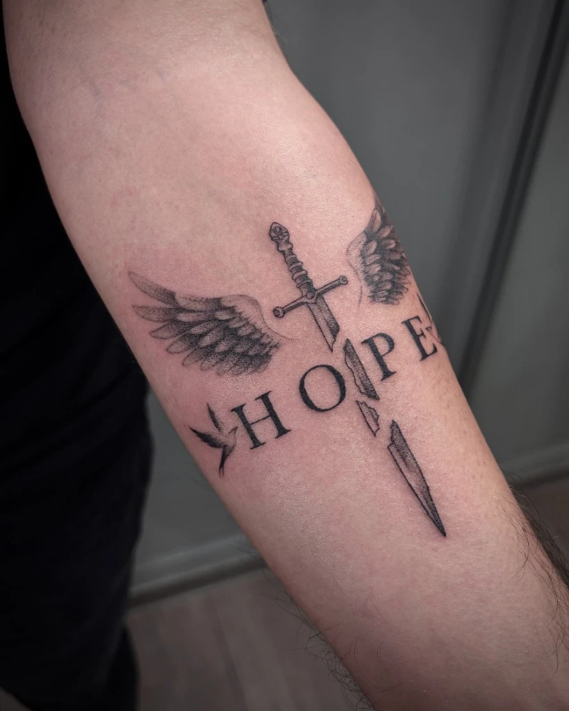 Tatuaj Fine Line cu sabie, aripi și text